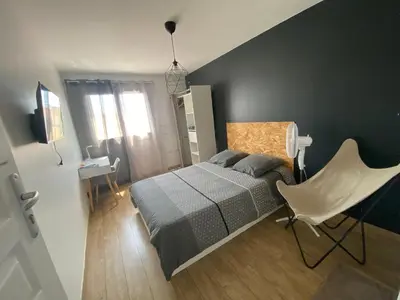a bedroom with a bed and a white chair at Appartement de 4 chambres proche plage, tram et aeroport in Nice