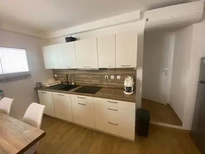 a kitchen with white cabinets and a wooden floor at Appartement de 4 chambres proche plage, tram et aeroport in Nice