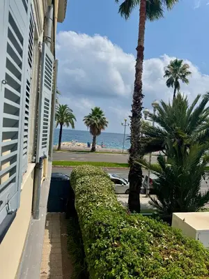 a building with palm trees and the ocean in the background at Cozy studio sur la promenade in Nice