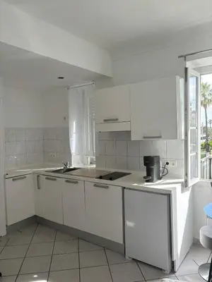 a white kitchen with white cabinets and a sink at Cozy studio sur la promenade in Nice