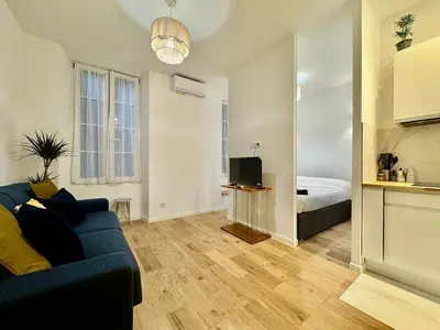 a living room with a blue couch and a bedroom at Charming Studio in the Heart of Nice in Nice