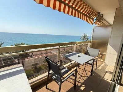 a balcony with a table and chairs and the ocean at Azur Promenade in Nice