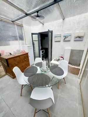 a dining room with a table and white chairs at Appartement Jardin 10mn centre in Nice