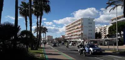 a city street with cars and a motorcycle and palm trees at Stella Maris in Cagnes-sur-Mer