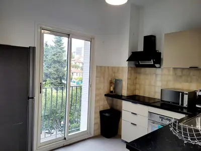 a kitchen with a large window and a kitchen with a counter at Séjour chic proche de la mer in Nice