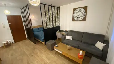 a living room with a couch and a clock on the wall at Appartement proche plage, aéroport, tram in Nice