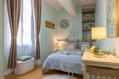 a bedroom with a bed and a clock on the wall at Charming flat, fully equipped, air conditioning, beach only 300m - LA LOGE in Nice