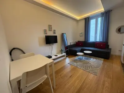 a living room with a black couch and a table at 2P place massena in Nice