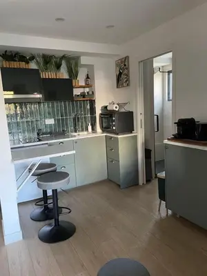 a kitchen with a counter and a table and a stool at Appartement Zephyr - à 1 minute de la plage in Cagnes-sur-Mer
