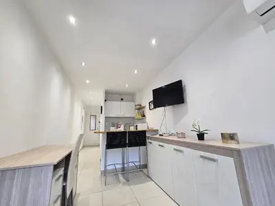 a kitchen with white cabinets and a tv on the wall at Sunny Prom Studio in Nice
