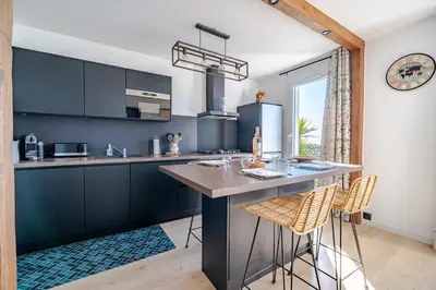 a kitchen with black cabinets and a large island with bar stools at Panoramic sea view of the French Riviera, Parking in Nice