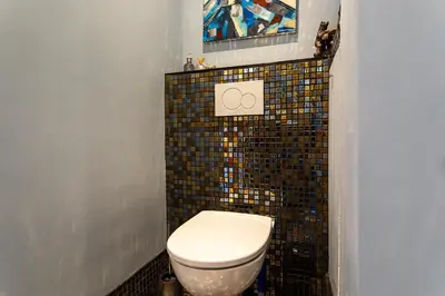 a bathroom with a toilet and a tile wall at LE ROYAL AP4456 by Riviera Holiday Homes in Nice