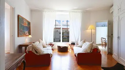 a living room with white furniture and a large window at Residence les Lauriers in Nice