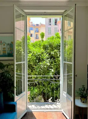 an open glass door looking out at a garden at Berlioz Blue AP4458 by Riviera Holiday Homes in Nice