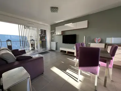 a living room with a couch and a table with purple chairs at 3 pièces central au pied de la promenade du paillon in Nice