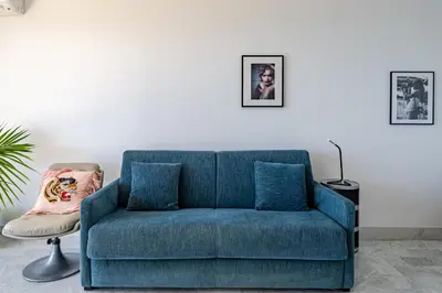 a blue couch in a living room with a chair at Studio Vue mer Parking Clim in Nice