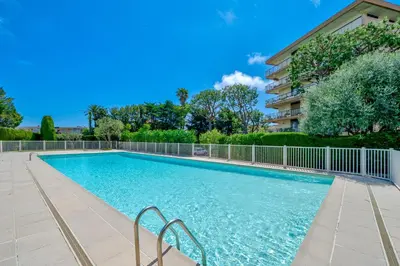 a swimming pool with a fence and a building at Studio Vue mer Parking Clim in Nice