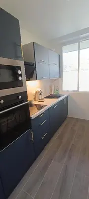 a kitchen with blue cabinets and a stove top oven at Appartement vue mer et panoramique, 2 chambres, 3 lits in Nice