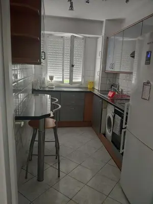 a small kitchen with a table and a refrigerator at 3 pièces 67m2 centre ville très lumineux et calme in Nice