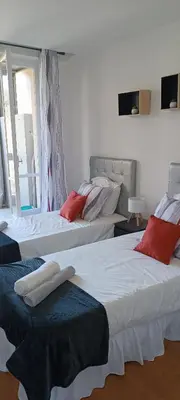 a room with three beds with red pillows on them at Nice, vue mer et panoramique in Nice