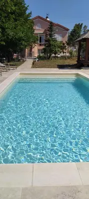 a swimming pool with blue water in front of a house at Beautiful Villa with large pool and garden 20 mn from Nice in Colomars