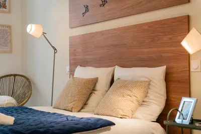 a bedroom with a bed with a wooden headboard and pillows at Charme et confort - centre ville de Nice in Nice