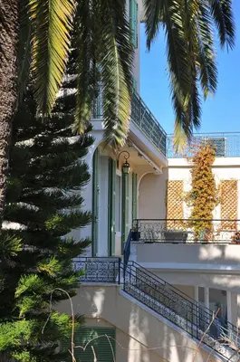 a white house with a palm tree in front of it at Luxury Villa Pool & Sea View in Nice