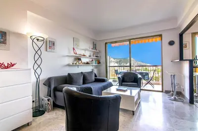 a living room with a couch and chairs and a table at 3 rooms panoramic sea view in Beaulieu-sur-Mer