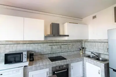 a kitchen with white cabinets and a sink and a microwave at 3 rooms panoramic sea view in Beaulieu-sur-Mer