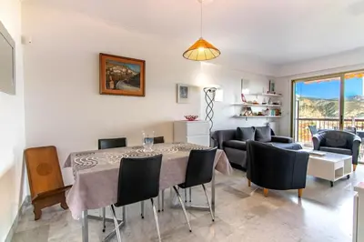 a living room with a dining room table and chairs at 3 rooms panoramic sea view in Beaulieu-sur-Mer