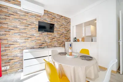 a kitchen with a table and chairs and a brick wall at Studio proche mer avec jardin in Nice