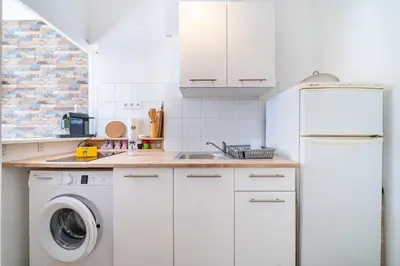 a kitchen with a white refrigerator and a washing machine at Studio proche mer avec jardin in Nice