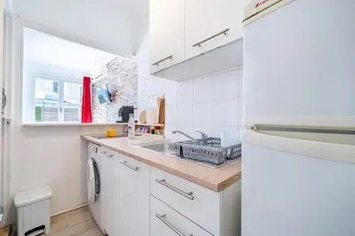 a white kitchen with a sink and a dishwasher at Studio proche mer avec jardin in Nice
