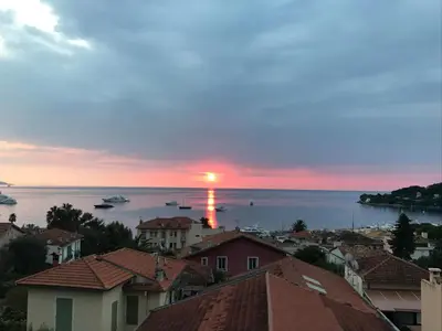 a sunset over a city with boats in the water at Suggestivo appartamento in Saint-Jean-Cap-Ferrat