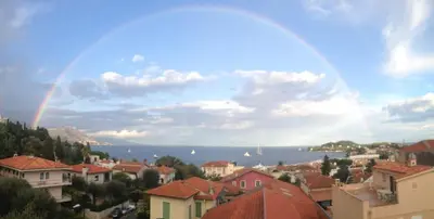 a rainbow in the sky over a city with houses at Suggestivo appartamento in Saint-Jean-Cap-Ferrat