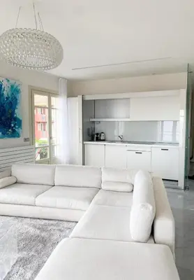 a white living room with a white couch and a kitchen at Suggestivo appartamento in Saint-Jean-Cap-Ferrat