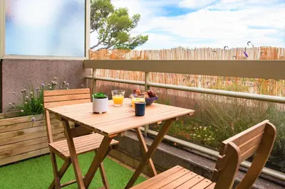 a wooden table with two chairs and drinks on a patio at Studio Premium au Calme avec Terrasse Vue Mer et Parking in Nice