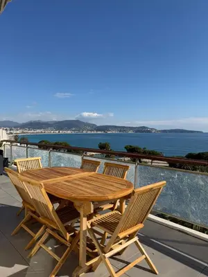 a wooden table and chairs on a balcony with the ocean at NICE, Exceptional Sea View, Top Floor, Parking in Nice