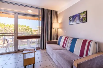 a living room with a couch and a balcony at Résidence Héliotel Marine in Saint-Laurent-du-Var