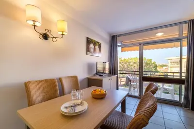 a dining room with a table and chairs and a window at Résidence Héliotel Marine in Saint-Laurent-du-Var