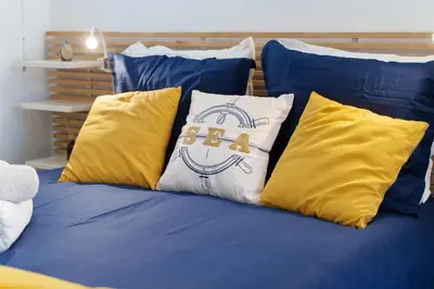 a bed with blue and yellow pillows with the word sleep at Nice Renting - 5b PENCHIENATTI - Charming Cozy Studio Balcony AC Massena in Nice