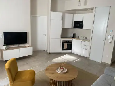 a living room with a couch and a table and a kitchen at Nice virgil Barel in Nice