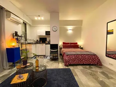 a bedroom with a large bed and a kitchen at Cosy studio à 2 pas de la mer in Nice