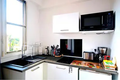 a kitchen with a black counter top with a microwave at Cosy studio à 2 pas de la mer in Nice