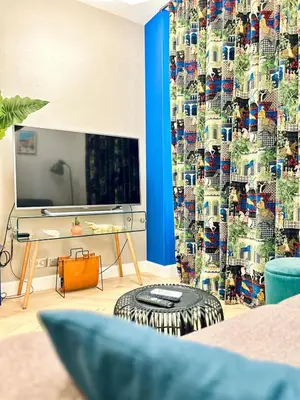 a living room with a tv and a blue curtain at Old Town Vibes - 5min to Sea - AC & Breakfast in Nice