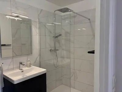 a bathroom with a glass shower and a sink at Spacieux 4P familial renové in Nice