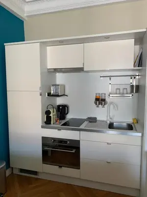 a kitchen with white cabinets and a sink at Lumineux Studio dernier étage avec terrasse, proche mer in Nice