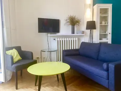 a living room with a blue couch and two chairs and a table at Lumineux Studio dernier étage avec terrasse, proche mer in Nice