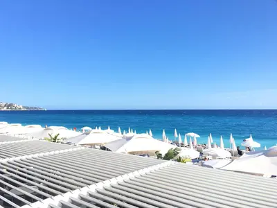 a view of the beach with umbrellas and the ocean at Lumineux Studio dernier étage avec terrasse, proche mer in Nice