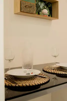a table with two glasses and a plate and a vase at Nice Magnan studio avec jardin proche des plages in Nice